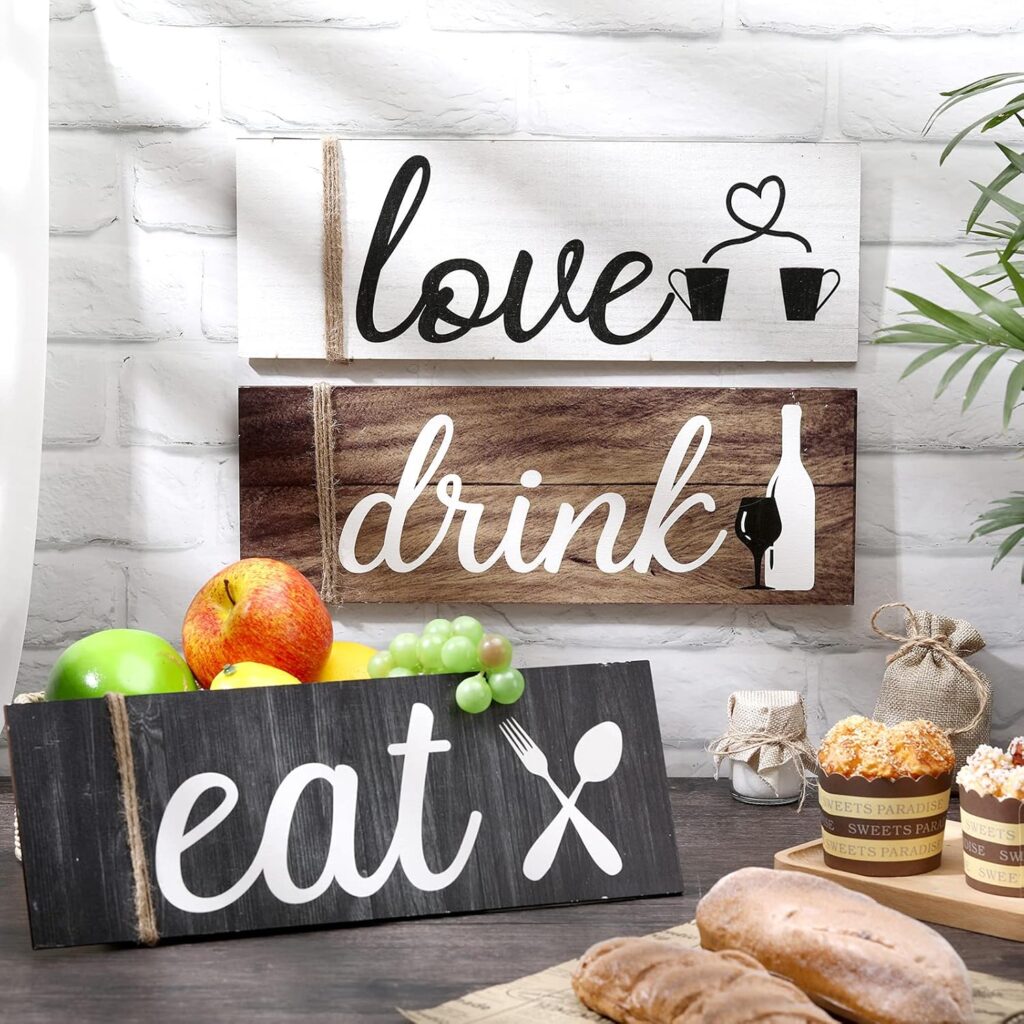 Wooden wall signs reading love with mugs, drink with a wine bottle and glass, and eat with utensils. A basket of fruits and pastries are on a table, with a white brick background.