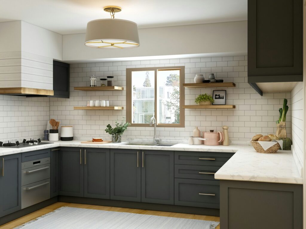 A modern kitchen with dark green cabinets, white countertops, and a white tile backsplash. Wooden shelves hold plants and kitchenware. A window is centered above the sink, and a round light fixture hangs from the ceiling. A rug covers part of the floor.